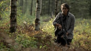 40 Acres cena com protagonista em floresta em momento de tensão e sobrevivência