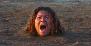 Zendaya como Rue Bennett enterrada até o pescoço no deserto gritando na 3ª temporada de Euphoria na HBO Max