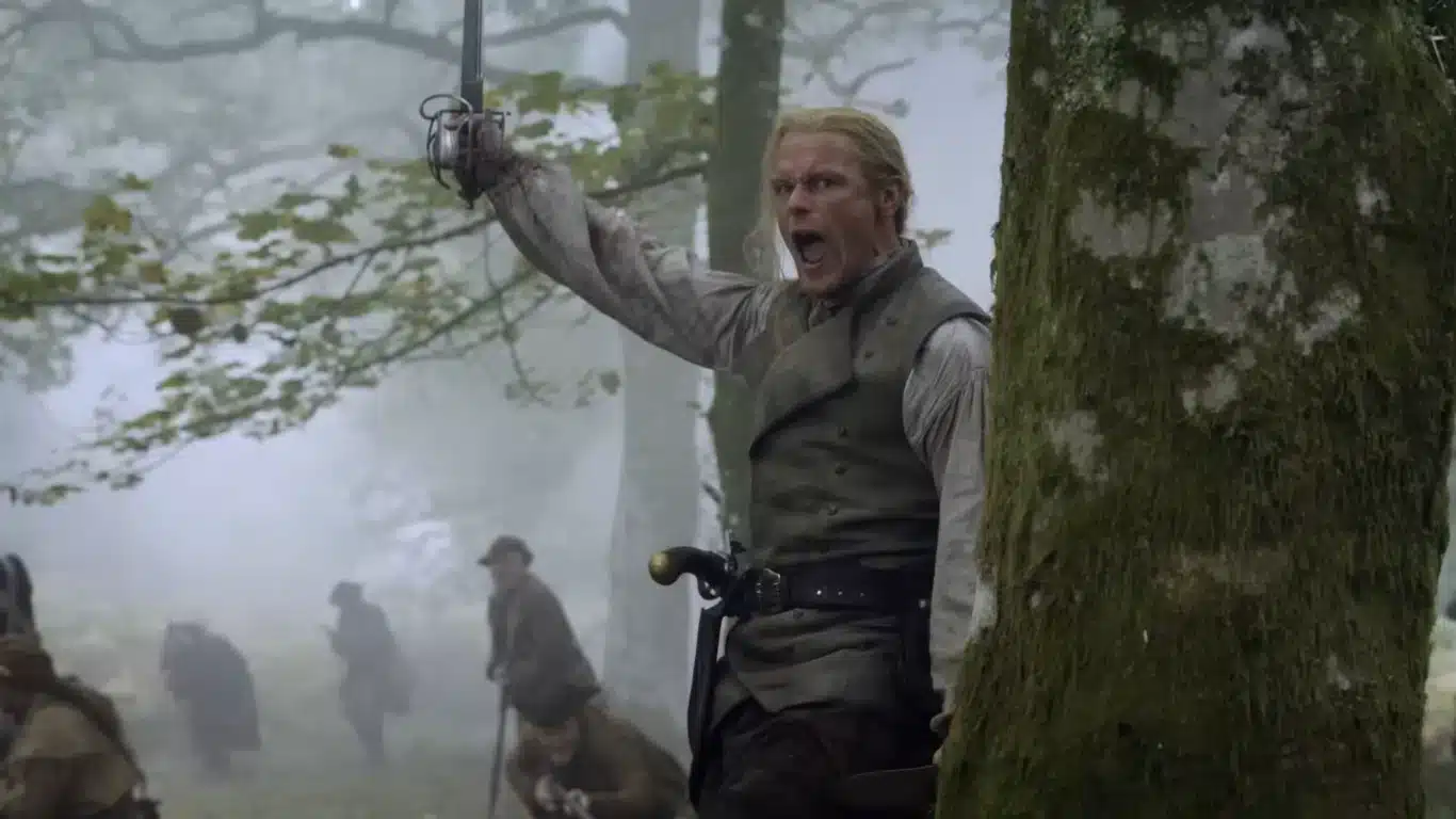 Sam Heughan como Jamie Fraser empunhando espada na Batalha de King's Mountain com soldados ao fundo no final da 8ª temporada de Outlander