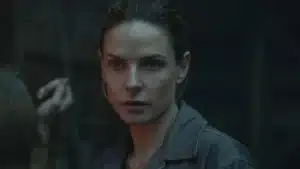 Rebecca Ferguson como Juliette Nichols se ajustando diante do espelho em uniforme de prefeita na 3ª temporada de Silo