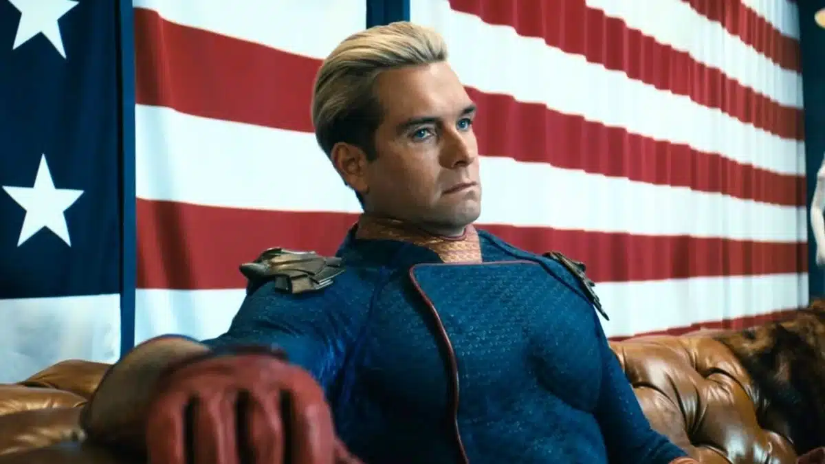 Antony Starr como Capitão Pátria sentado em frente à bandeira americana em cena de The Boys no Prime Video