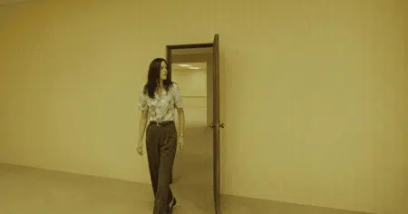 Corredor amarelado dos Backrooms com iluminação fluorescente e personagens perdidos no filme de terror da A24