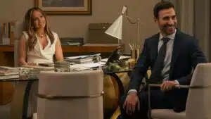 Jennifer Lopez como Jackie Cruz, CEO da Air Cruz em Paixão de Escritório, usando traje executivo em cenário de escritório corporativo