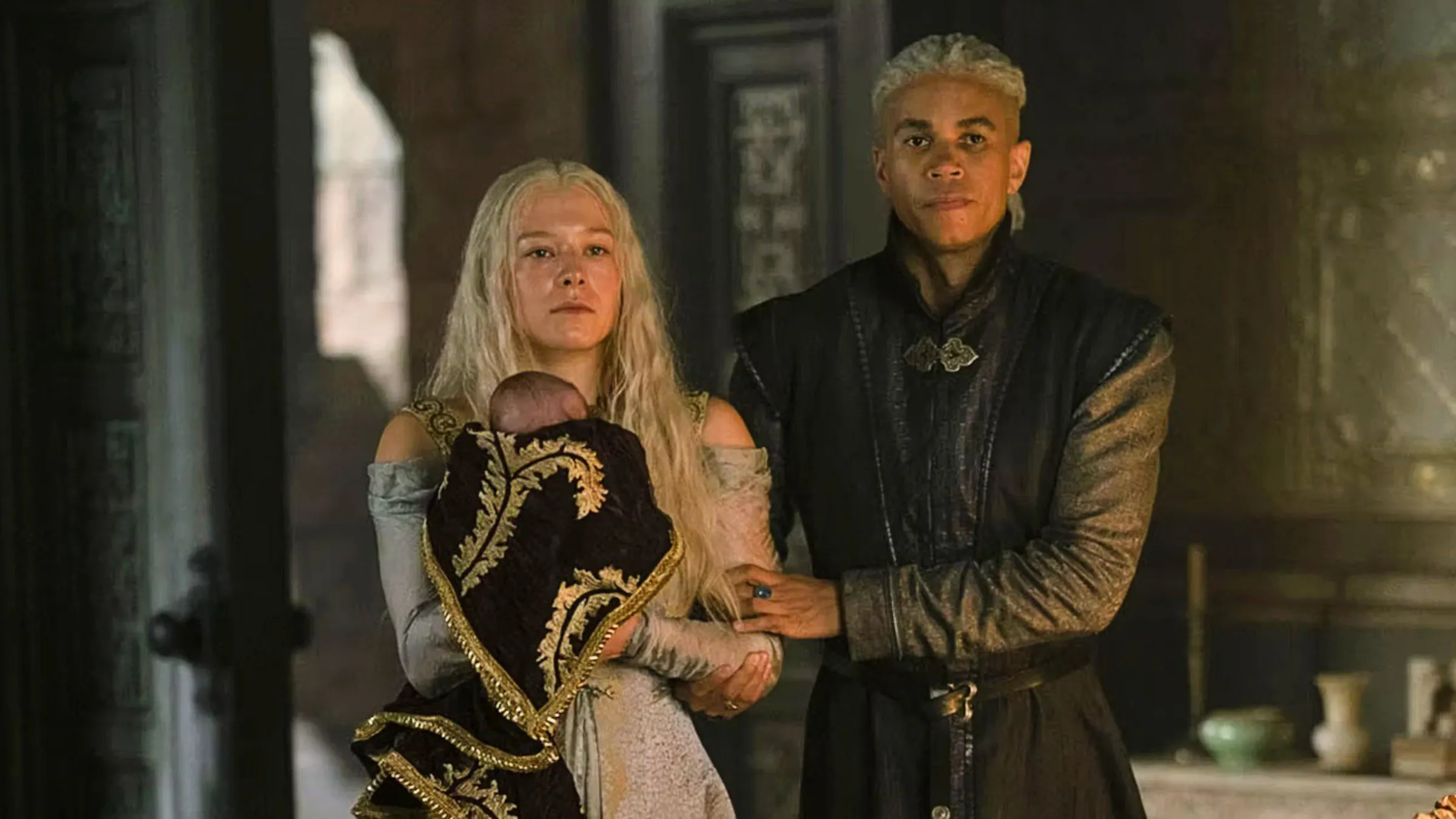 Rhaenyra Targaryen holding a baby with Laenor Velaryon next to her in House of the Dragon