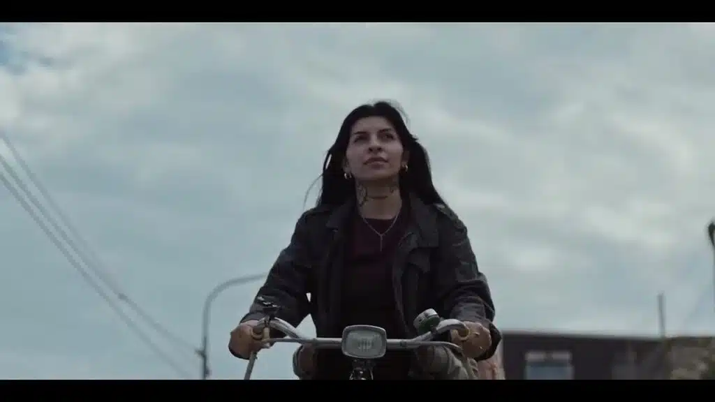 Risa e o Telefone do Vento: O Filme Argentino da Netflix que Vai Fazer Você Chorar Cazzu como Sara pedalando sozinha em ângulo baixo em cena de Risa e o Telefone do Vento na Netflix