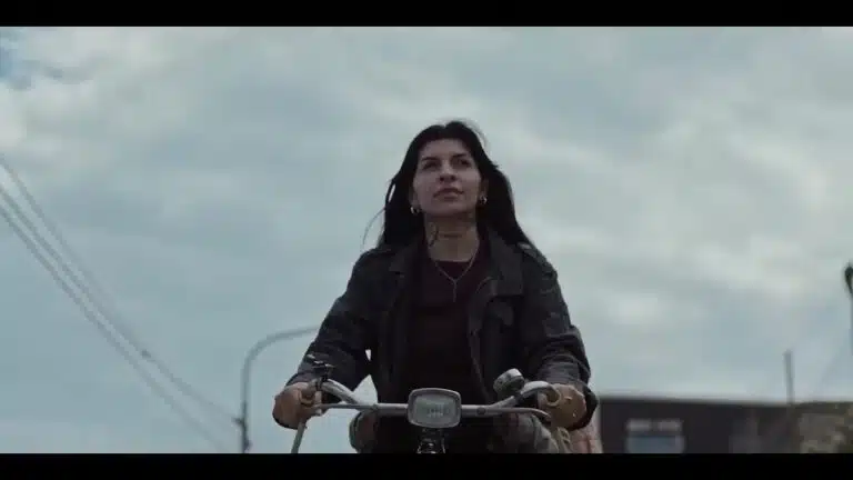 Cazzu como Sara pedalando sozinha em ângulo baixo em cena de Risa e o Telefone do Vento na Netflix