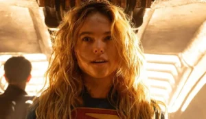 Milly Alcock como Supergirl em pose heroica com traje da personagem