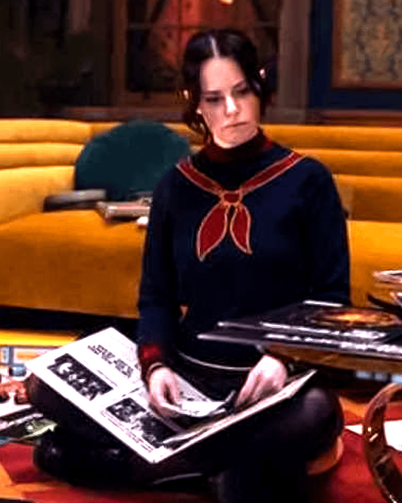 Emily Hampshire como EDITH sentada entre documentos em cena de VisionQuest