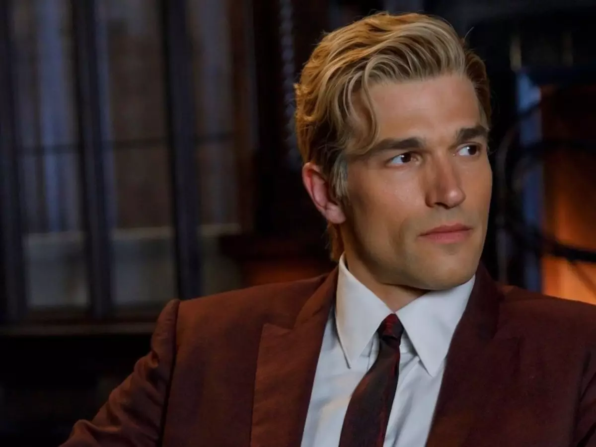 Personagem sentado de perfil em ambiente escuro da série American Horror Story temporada 13